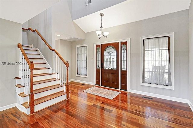 foyer featuring lofted ceiling, a healthy amount of sunlight, hardwood / wood-style floors, and a chandelier