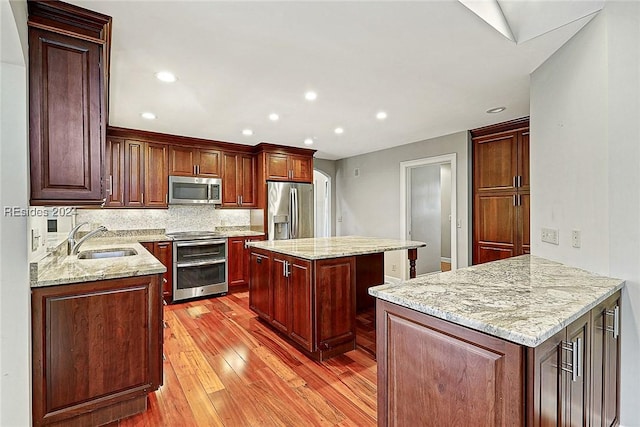 kitchen with light stone countertops, appliances with stainless steel finishes, a center island, and kitchen peninsula