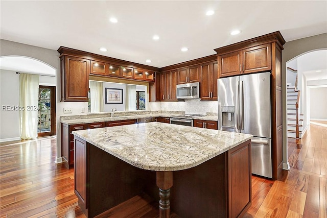 kitchen featuring wood-type flooring, appliances with stainless steel finishes, a center island, and sink