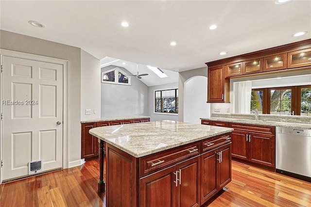 kitchen featuring vaulted ceiling, dishwasher, sink, a center island, and light stone counters