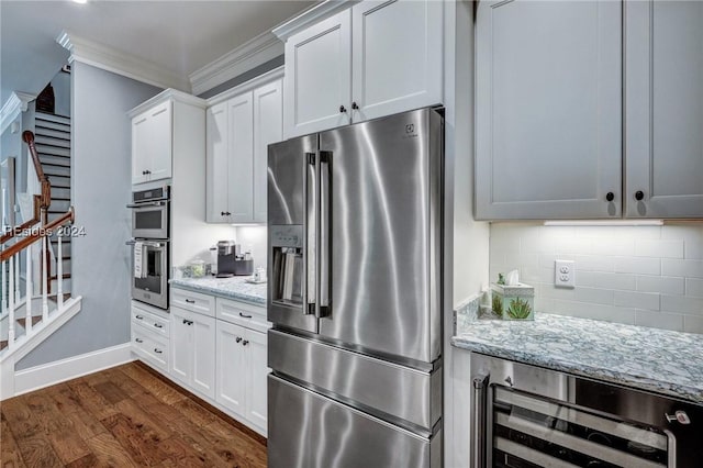 kitchen with light stone counters, white cabinetry, beverage cooler, and appliances with stainless steel finishes