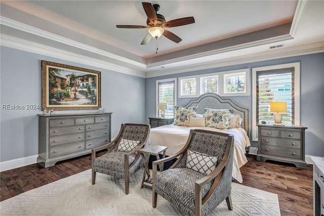 bedroom featuring dark hardwood / wood-style flooring, a tray ceiling, ornamental molding, and ceiling fan