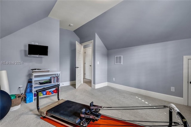 exercise area featuring vaulted ceiling and light colored carpet