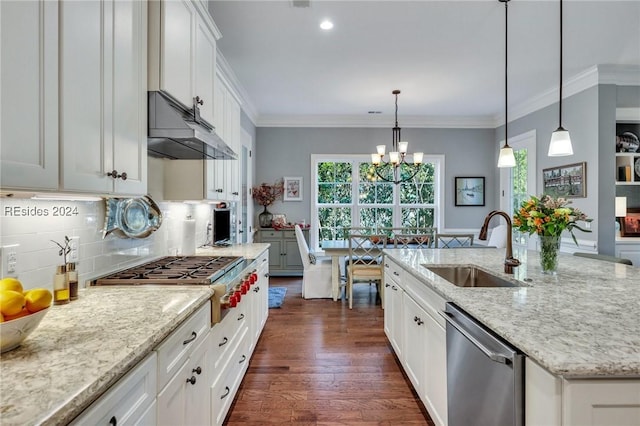 kitchen with pendant lighting, white cabinetry, sink, stainless steel appliances, and a center island with sink