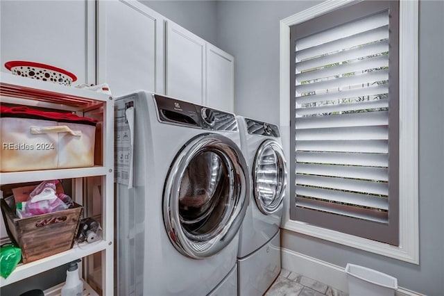 clothes washing area featuring cabinets and washing machine and clothes dryer