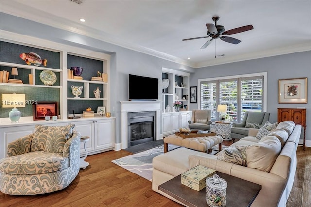 living room featuring hardwood / wood-style flooring, crown molding, ceiling fan, and built in shelves