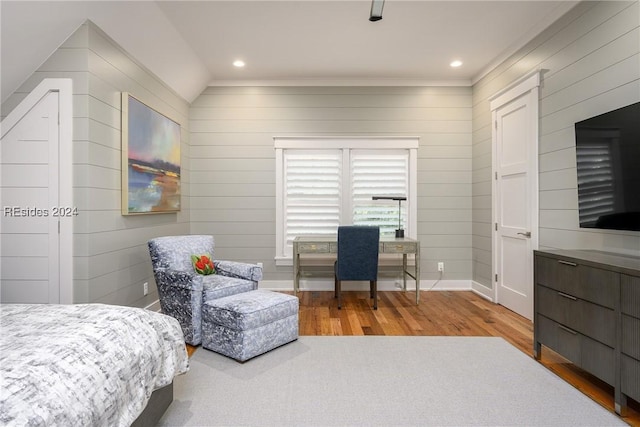 bedroom with vaulted ceiling, wooden walls, hardwood / wood-style floors, and ceiling fan