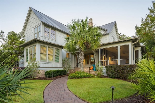 view of front of home featuring a sunroom and a front lawn