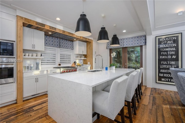 kitchen with sink, decorative light fixtures, a center island with sink, appliances with stainless steel finishes, and white cabinets