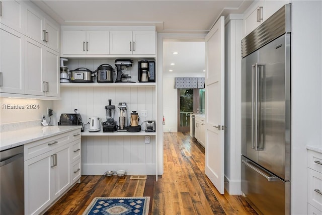 kitchen with white cabinetry, light stone counters, dark wood-type flooring, and stainless steel appliances