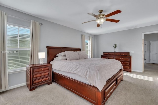 bedroom featuring multiple windows, light carpet, and ceiling fan