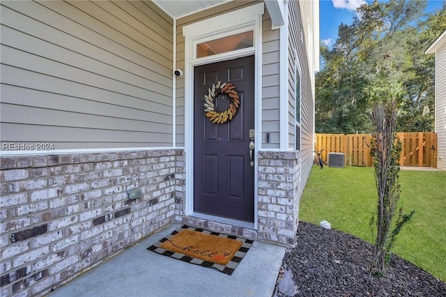 property entrance with cooling unit and a yard