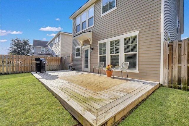 wooden deck featuring a grill and a lawn