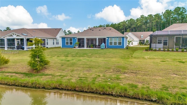 rear view of house with a water view, a yard, glass enclosure, and a sunroom