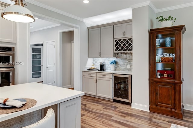 kitchen with wine cooler, ornamental molding, double oven, and hanging light fixtures