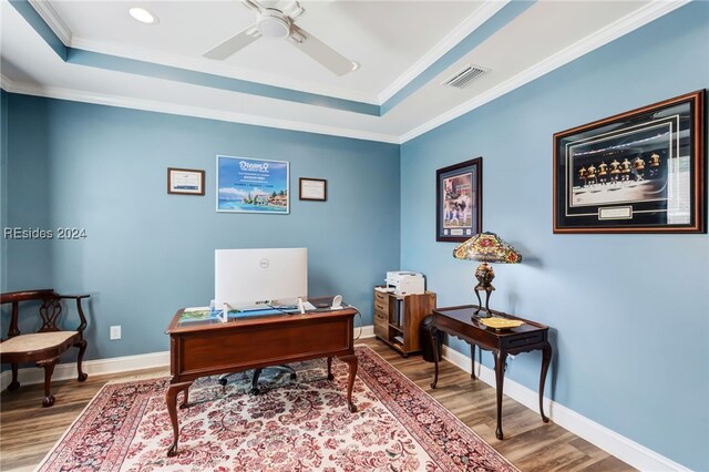 home office featuring crown molding, wood-type flooring, a raised ceiling, and ceiling fan