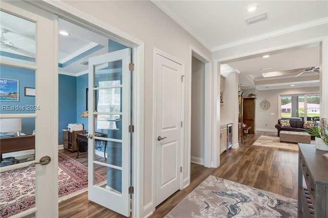 corridor featuring crown molding, dark wood-type flooring, and a tray ceiling