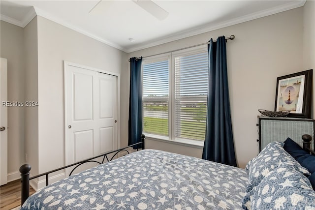 bedroom with hardwood / wood-style flooring, ceiling fan, ornamental molding, and a closet