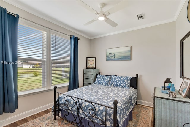 bedroom with multiple windows, crown molding, wood-type flooring, and ceiling fan