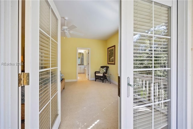 doorway to outside with light carpet and ceiling fan