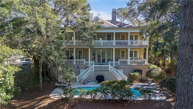 rear view of house featuring a patio, a balcony, and french doors