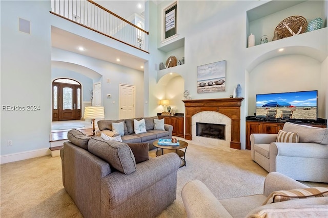 living room featuring a premium fireplace, a towering ceiling, and light carpet