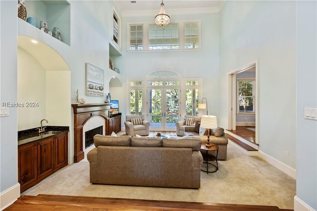 living room featuring a towering ceiling, light colored carpet, and french doors