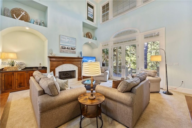 living room with french doors, a premium fireplace, and a high ceiling