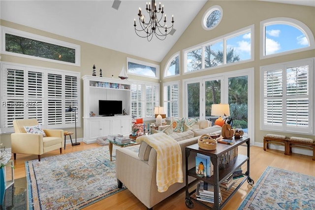 living room featuring light wood-type flooring, a chandelier, and high vaulted ceiling