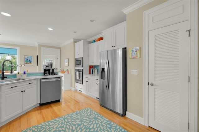 kitchen featuring white cabinetry, appliances with stainless steel finishes, sink, and crown molding