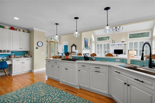 kitchen with sink, decorative light fixtures, white cabinets, and backsplash