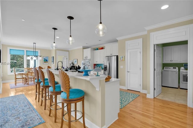 kitchen featuring stainless steel refrigerator with ice dispenser, a spacious island, decorative light fixtures, and white cabinets