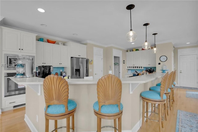 kitchen featuring appliances with stainless steel finishes, a kitchen breakfast bar, decorative backsplash, and white cabinets