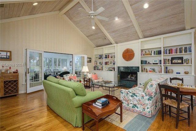 living room with light hardwood / wood-style flooring, a premium fireplace, beam ceiling, high vaulted ceiling, and built in shelves