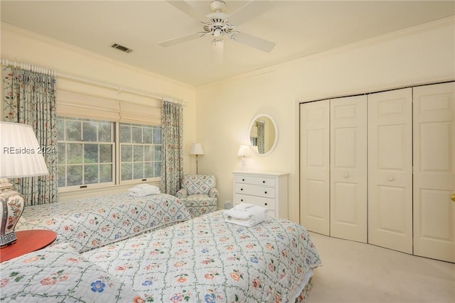 carpeted bedroom with ornamental molding, a closet, and ceiling fan