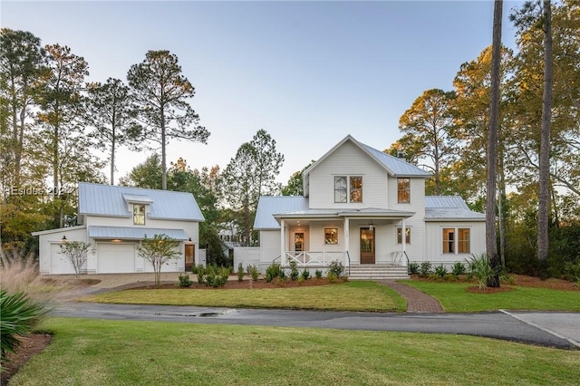 view of front of home featuring a garage, a front yard, and covered porch