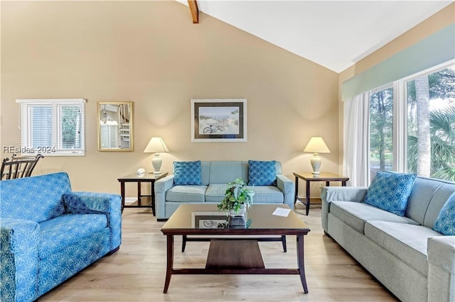 living room featuring plenty of natural light, lofted ceiling with beams, and light wood-type flooring