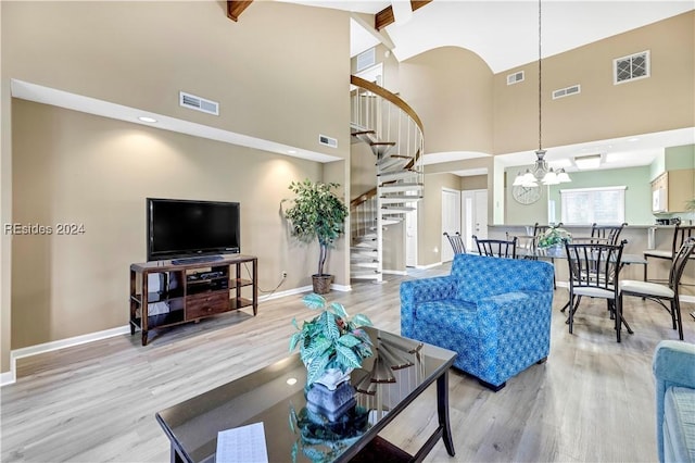 living room with an inviting chandelier, hardwood / wood-style floors, and a high ceiling