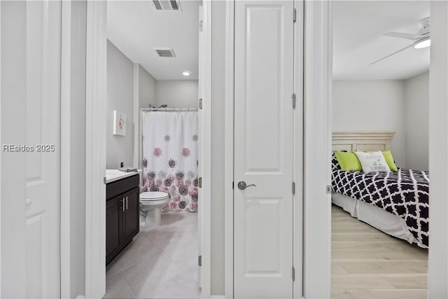 full bathroom featuring hardwood / wood-style flooring, ceiling fan, vanity, toilet, and shower / bath combo with shower curtain