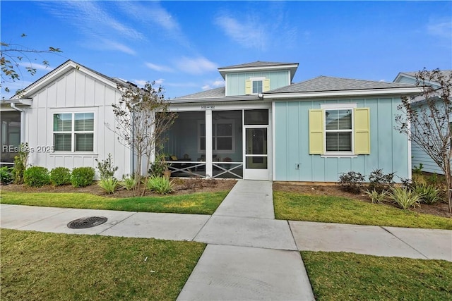 bungalow-style house featuring a sunroom and a front lawn