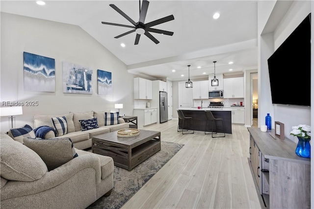 living room featuring ceiling fan, vaulted ceiling, and light hardwood / wood-style flooring