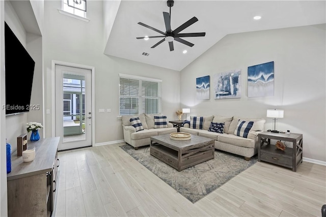 living room featuring a high ceiling, ceiling fan, and light hardwood / wood-style floors