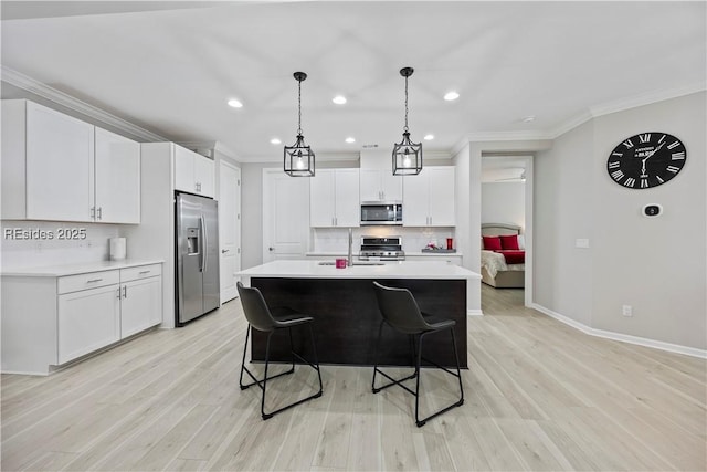 kitchen with white cabinetry, light hardwood / wood-style floors, stainless steel appliances, and an island with sink