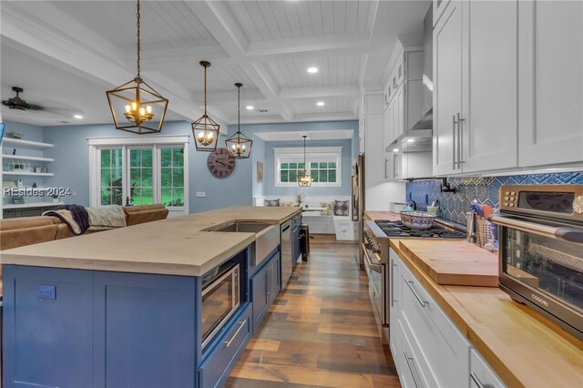 kitchen featuring appliances with stainless steel finishes, decorative light fixtures, blue cabinets, white cabinetry, and wooden counters