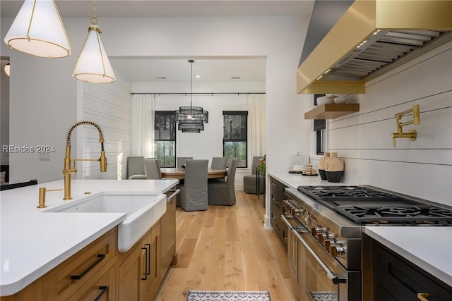 kitchen featuring appliances with stainless steel finishes, sink, hanging light fixtures, and custom range hood