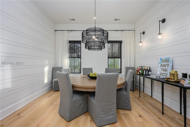 dining area with light hardwood / wood-style floors and a notable chandelier