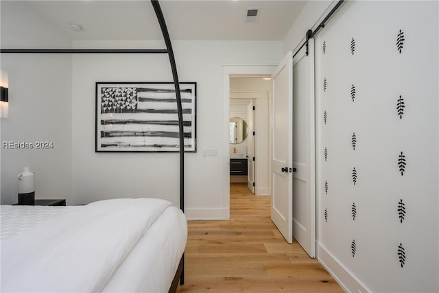 bedroom featuring light hardwood / wood-style floors and a barn door