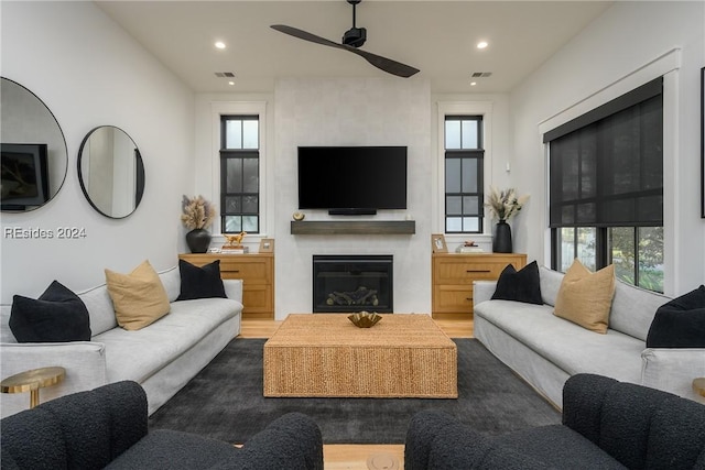 living room featuring a large fireplace and ceiling fan