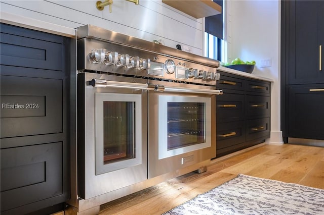 bar with double oven range, blue cabinetry, and light wood-type flooring