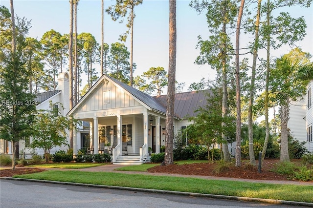 modern farmhouse style home with a front yard and covered porch